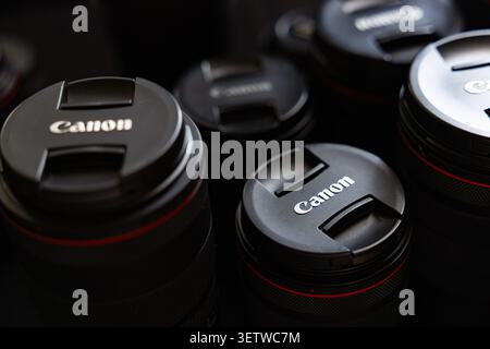 Lemberg, Ukraine - 21. Juni 2026: Gruppe professioneller Canon Kameraobjektive mit Schutzkappen auf dunklem Hintergrund Stockfoto