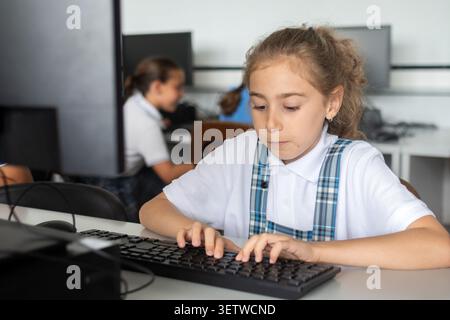 Grundschüler mit einem Desktop-Computer während eines IT-Unterrichts. Stockfoto