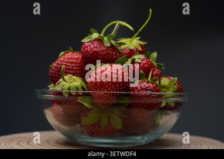 Rote Erdbeeren in Glasschale auf dunklem Hintergrund Stockfoto