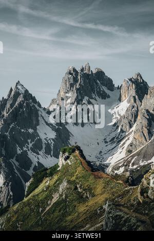Auronzo di Cadore, Italien - 07. Juni 2024: Blick auf die zerklüfteten Gipfel von Cadini di Misurina mit einem Wanderer, der auf einem schmalen Kamm steht. Stockfoto