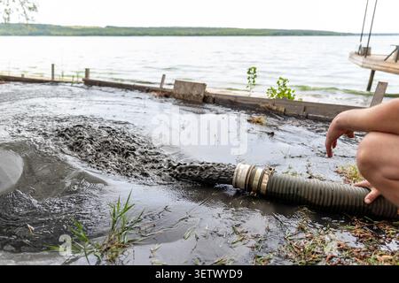 Engeneer halten Rohr der Pumpe Maschine Gießen Schlamm Schlamm Schlamm Abwasser mit Sandschlamm auf dem Boden. Sand-waschen und Küste-depeening. Septische Abwässer Stockfoto