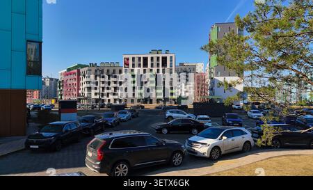 Minsk Weißrussland 20. März 2026 Moderne Wohngegend mit geparkten Autos und Mehrfamilienhäusern unter klarem Himmel. Das Stadtviertel zeigt zeitgenössische Ho Stockfoto