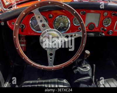 TAVERNES BLANQUES, SPANIEN - 14. JUNI 2026. Nahaufnahme zeigt ein Vintage-Dreispeichen-Lenkrad aus Holz und Retro-Instrumentenanzeigen in einem klassischen MG-MG Stockfoto