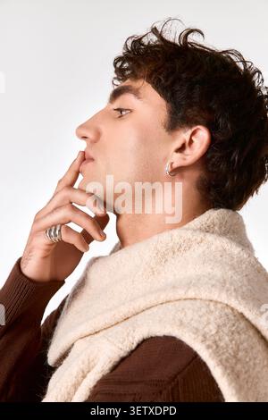 Ein gutaussehender junger Mann steht selbstbewusst und zeigt sein modisches Outfit und seine auffälligen Details. Stockfoto