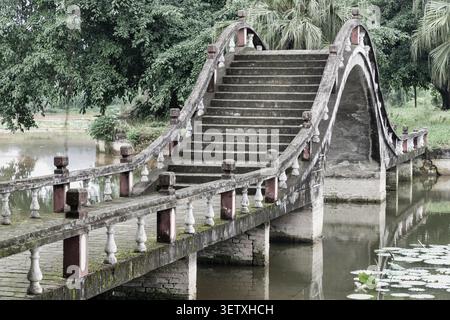 Chongqing, China - 09. Juni 2026 - im Dazu Lotus Manor erhebt sich eine traditionelle Steinbrücke in einen dramatischen, steil gestuften Bogen. Eingerahmt von kunstvollen Balustr Stockfoto