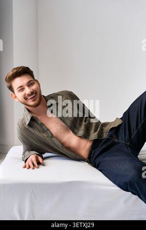 Ein bärtiger junger Mann entspannt sich souverän in einem stilvollen Outfit im Studio Stockfoto