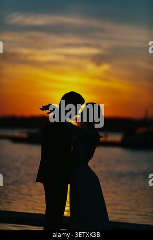 Romantische Silhouette eines Paares bei Sonnenuntergang am Wasser Stockfoto