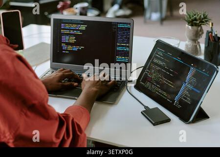 Black Woman Coding auf Laptops und Tablets für die Softwareentwicklung Stockfoto