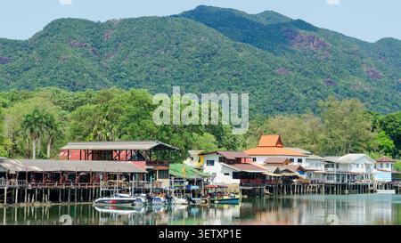 Die Pfahlbauten des Fischerdorfes säumen den Bang bao Pier mit tropischen Bergen in thailand Stockfoto