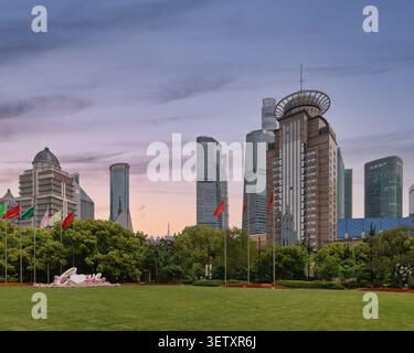 Shanghai, China - 4. Mai 2026: Blick auf die Skyline von Lujiazui mit Wolkenkratzern und einem Park im Vordergrund mit einer großen rosafarbenen Blumenskulptur von LOVE unter einem wunderschönen Sonnenuntergang Stockfoto