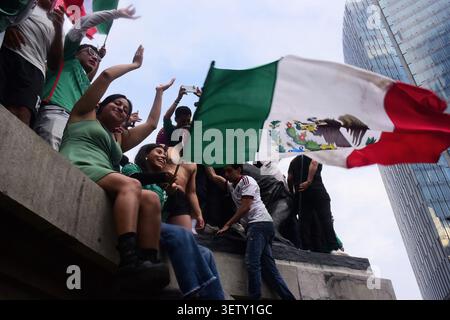 Mexikanische Fans klettern während der WM auf die Statuen des Engels der Unabhängigkeit und schwenken Flaggen. Stockfoto