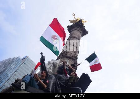 Mexikanische Fans klettern während der WM auf die Statuen des Engels der Unabhängigkeit und schwenken Flaggen. Stockfoto