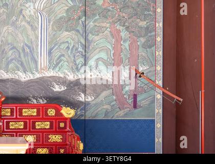 Nahaufnahme des Innenraums des königlichen Irworobongdo-Leinwandgemäldes und eines kunstvoll verzierten roten Lackthronen-Tagesbetts im Gyeongbokgung-Palast. Stockfoto
