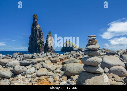 Ein ausgeglichener Zen-Steinstapel auf einem Kiesstrand mit majestätischen vulkanischen Meeresfelsen im Hintergrund, Madeira, Strand von Ribeira da Janela, Portugal Stockfoto
