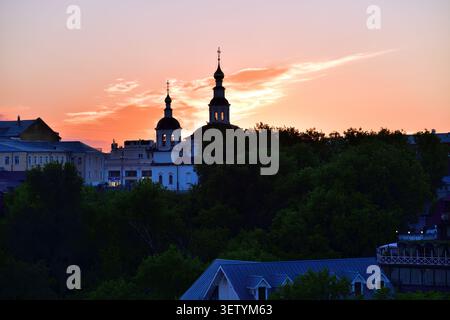 Kuppeln einer Kirche und Dächer alter Gebäude aus dem 19. Jahrhundert im historischen Teil von Wladimir, die bei Sonnenuntergang von der Aussichtsplattform im Puschkin Park gezeigt werden. Russ Stockfoto