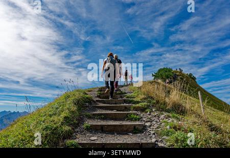 Wanderer klettern auf die Steinstufen des Stoos Ridge Trail, einem atemberaubenden blauen Himmel, der sich endlos über ihnen erstreckt Stockfoto