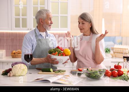 Nettes Seniorenpaar, das zusammen kocht. Frau und Mann halten Sieb mit frischem Gemüse in der Küche Stockfoto