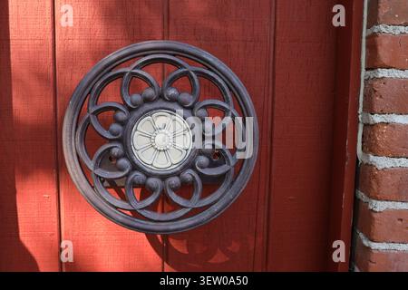 Dekorative schmiedeeiserne Wanddekoration an einer roten hölzernen Außenwand in Reeder's Alley, Helena, Montana, USA. Stockfoto