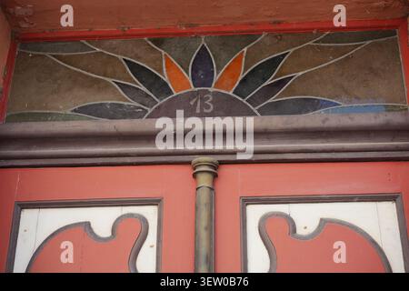 Architektonisches Detail eines historischen Türspiegels mit stilisiertem floralem Buntglasfenster mit Haus Nr. 13 in Stralsund, Deutschland. Stockfoto