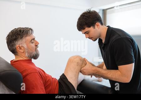 Physiotherapeut mit manueller Physiotherapie am Knie Stockfoto