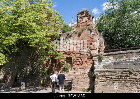 Menschen gehen auf dem Severn Way neben dem Fluss Severn und betrachten die Sandsteinmauer der mittelalterlichen Stadtbefestigung. Worcester, England Stockfoto