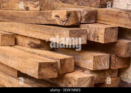 Großer Stapel von groben quadratischen Holzbalken, braunes Holz mit Rissen und Körnung, Seitenansicht der Konstruktion und Holzfällmaterialien Stockfoto