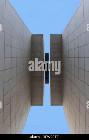 Moderne architektonische Betonwände, die eine symmetrische abstrakte Komposition schaffen, zeigen minimalistisches Design und starke geometrische Linien gegen einen Klon Stockfoto