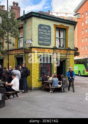 Historisches Public House mit grüner gefliester Fassade und Sitzgelegenheiten im Freien. Manchester, Großbritannien. Stockfoto