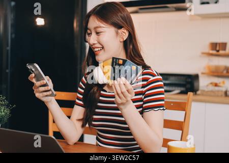 Glück Unternehmer schönes Geschäft asiatische junge Frau tragen lässig Handy zum Einkaufen online genießen Sie mit sozialen Medien und Laptop zu Hause Stockfoto
