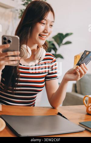 Glück Unternehmer schönes Geschäft asiatische junge Frau tragen lässig Handy zum Einkaufen online genießen Sie mit sozialen Medien und Laptop zu Hause Stockfoto
