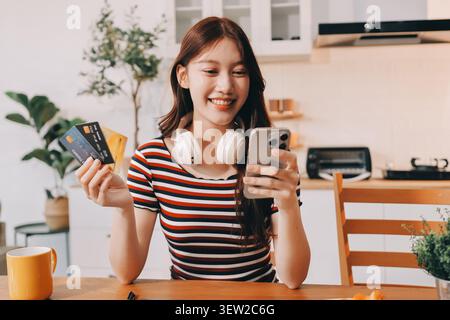 Glück Unternehmer schönes Geschäft asiatische junge Frau tragen lässig Handy zum Einkaufen online genießen Sie mit sozialen Medien und Laptop zu Hause Stockfoto