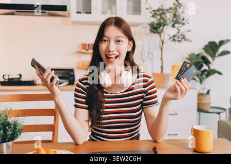Glück Unternehmer schönes Geschäft asiatische junge Frau tragen lässig Handy zum Einkaufen online genießen Sie mit sozialen Medien und Laptop zu Hause Stockfoto