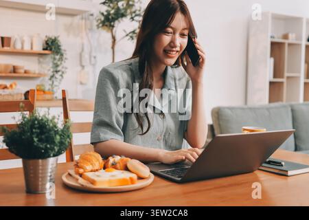 Glück Unternehmer schönes Geschäft asiatische junge Frau tragen lässig Handy zum Einkaufen online genießen Sie mit sozialen Medien und Laptop zu Hause Stockfoto