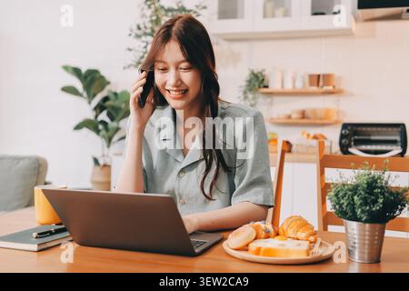 Glück Unternehmer schönes Geschäft asiatische junge Frau tragen lässig Handy zum Einkaufen online genießen Sie mit sozialen Medien und Laptop zu Hause Stockfoto