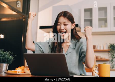 Glück Unternehmer schönes Geschäft asiatische junge Frau tragen lässig Handy zum Einkaufen online genießen Sie mit sozialen Medien und Laptop zu Hause Stockfoto