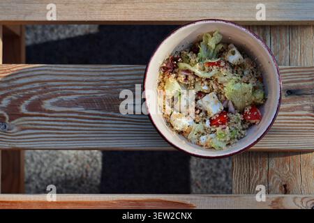 Frischer mediterraner Couscous-Salat mit Fetakäse in Schüssel auf Holztisch Stockfoto