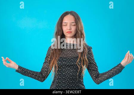 Frau, die mit beiden Händen in einer Geste der Offenheit und des Willkommenslächelns steht Stockfoto
