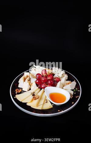 Raffinierte Studio-Aufnahme einer luxuriösen Käseplatte mit einer Vielzahl von Käsesorten, harten, weichen und blauen Sorten, die wunderschön mit Cluster angeordnet sind Stockfoto