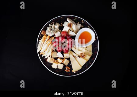 Ein atemberaubendes, flaches kommerzielles Foto von einer Gourmet-Käseplatte mit Brie, Blauschimmelkäse, Parmesan und handwerklicher Auswahl, garniert mit Re Stockfoto