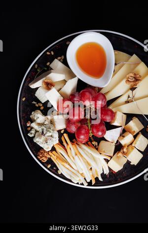 Ein atemberaubendes, flaches kommerzielles Foto von einer Gourmet-Käseplatte mit Brie, Blauschimmelkäse, Parmesan und handwerklicher Auswahl, garniert mit Re Stockfoto