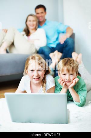 Entspannen Sie sich, porträtieren Sie Ihre Kinder auf dem Boden mit einem Laptop, einer Zeichentrickserie oder einem Film-Streaming. Glücklich, Eltern oder Kinder zu Hause mit Technik, Multimedia Stockfoto