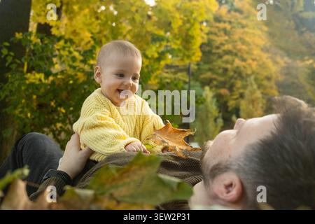 Vater und Baby genießen Herbstlaub Stockfoto