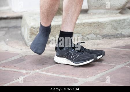 BANGKOK, THAILAND - 3. Juni 2026: Mann trägt schwarze Sneakers, Hochwinkelansicht. Stockfoto