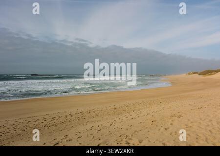 Leerer Sandstrand mit Meereswellen an einem bewölkten Tag Stockfoto