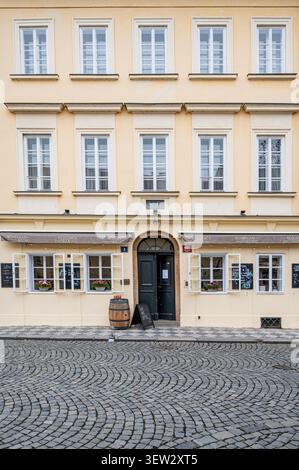 Vorderfassade des Bohemian Bistro und der Rezidence Dvorak mit einer traditionellen Holztür und einem Fass auf einer Kopfsteinpflasterstraße am Tag in Prag Stockfoto