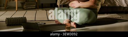 Schwangere Frau in Übergröße, die zu Hause pränatales Yoga praktiziert Stockfoto