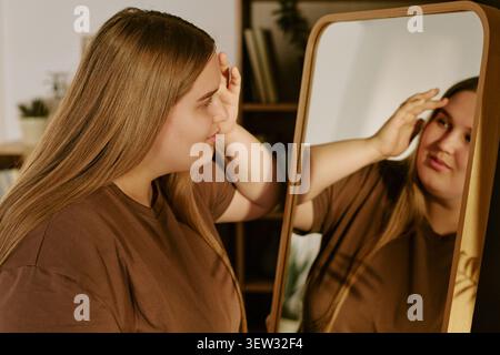 Frau in Übergröße, die im Spiegel für Selbstakzeptanzkampagne sucht Stockfoto