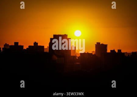 Ein dramatischer Sonnenuntergang erfüllt den Himmel mit leuchtenden Orange- und Gelbtönen, die die Gebäude von New York City in eine dunkle, scharfe Silhouette verwandeln. Der Glanz Stockfoto