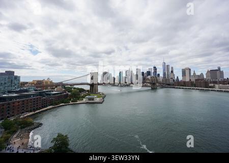 Die berühmte Brooklyn Bridge, die sich über den East River erstreckt, mit der dichten Skyline von Lower Manhattan, einschließlich One World Trade Stockfoto