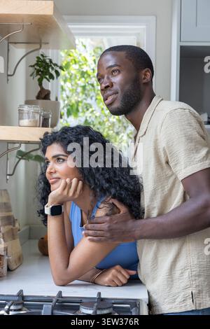 Diverse Paare, die sich auf der Theke beugen, Mann, der Hand auf der Frau liegend mit blauem Oberteil neben dem Kochfeld Stockfoto